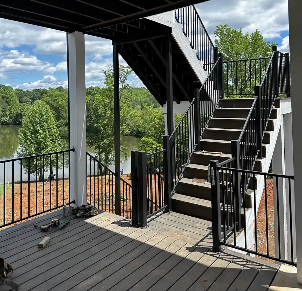Deck stairs with black metal railing leading down toward a lake