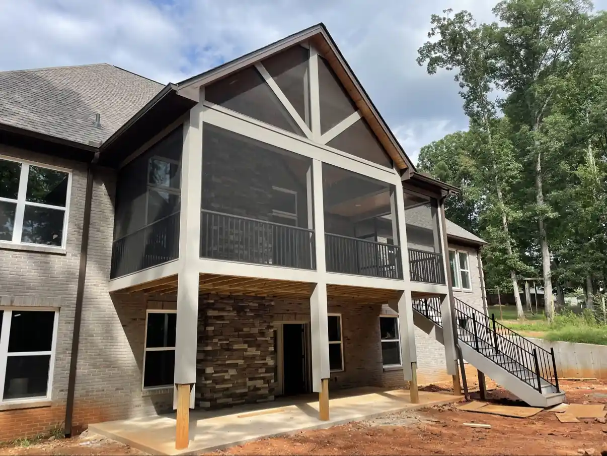 Brick home with an elevated gabled screen porch, black railing inside, and exterior stairs