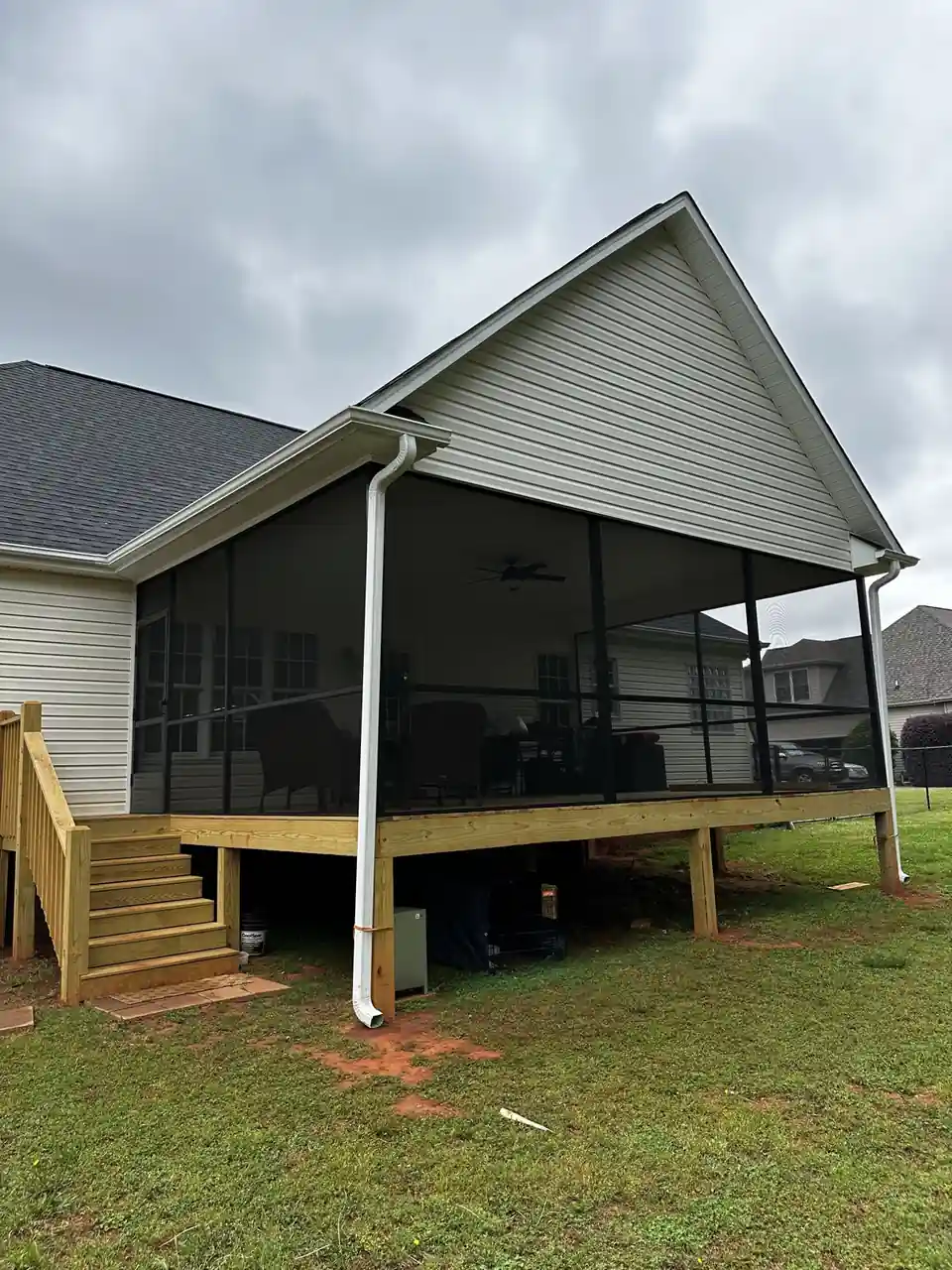 Finished elevated screen porch with a gabled roof on a wood deck with stairs