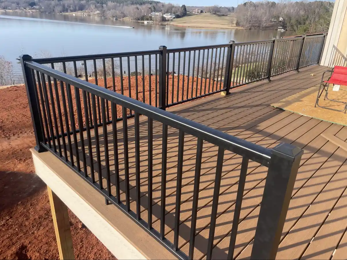 Black aluminum railing on a brown composite deck overlooking a lake