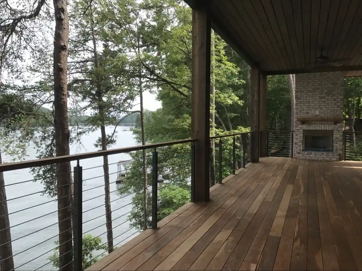 Horizontal cable railing along a lakeside wood deck with a brick fireplace